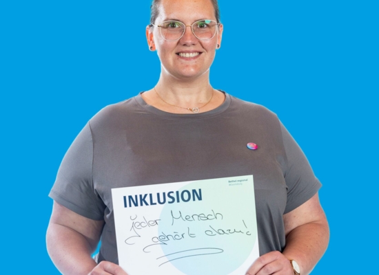 Frau mit Schild Inklusion jeder Mensch gehört dazu!