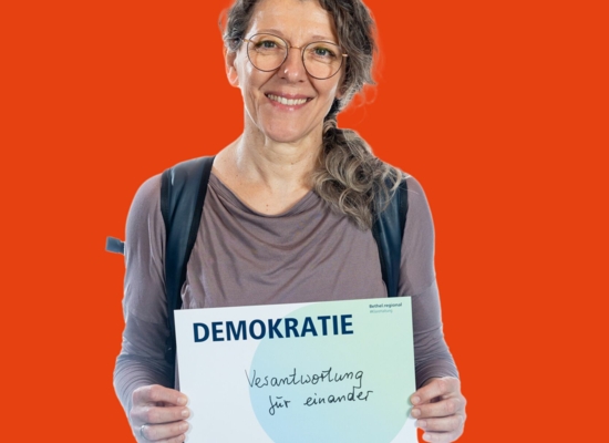 Frau mit Schild Demokratie Verantwortung für einander.