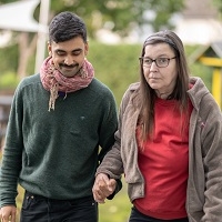 Ein Betreuer geht mit einer Klientin durch den Garten des Hauses an der Breslaustraße