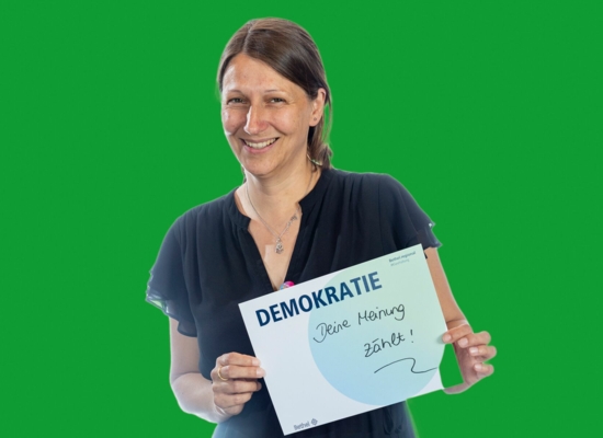 Frau mit Schild Demokratie Deine Meinung zählt!