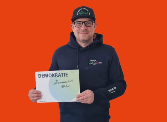 Mann mit Schild in der Hand Demokratie Zusammenhalt stärken.