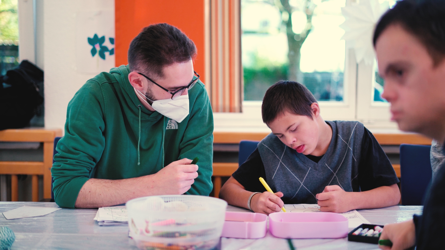 Das Bild zeigt den Heilerziehungspfleger in Ausbildung mit einem Jungen beim Malen.