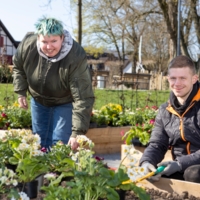 Eine Bewohnerin und ein Bewohner des Hauses Luisenstraße von Bethel.regional bepflanzt Hochbeete für die Landesgartenschau Höxter.