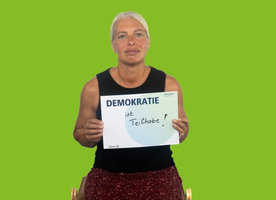 Frau mit Schild Demokratie ist Teilhabe!