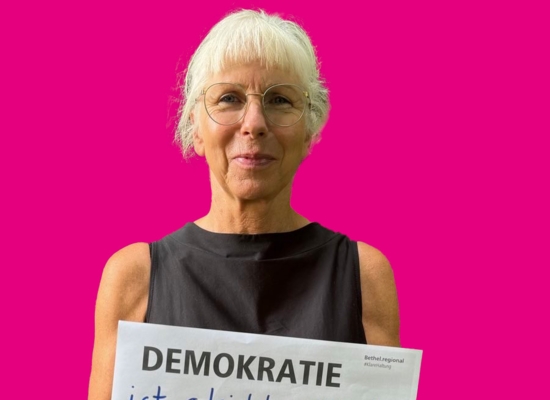 Frau mit Schild in der Hand Demokratie ist gleichberechtigter Zugang zu einem selbstbestimmten Leben.