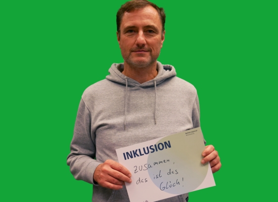 Mann mit Schild in der Hand Inklusion Zusammen, das ist das Glück!