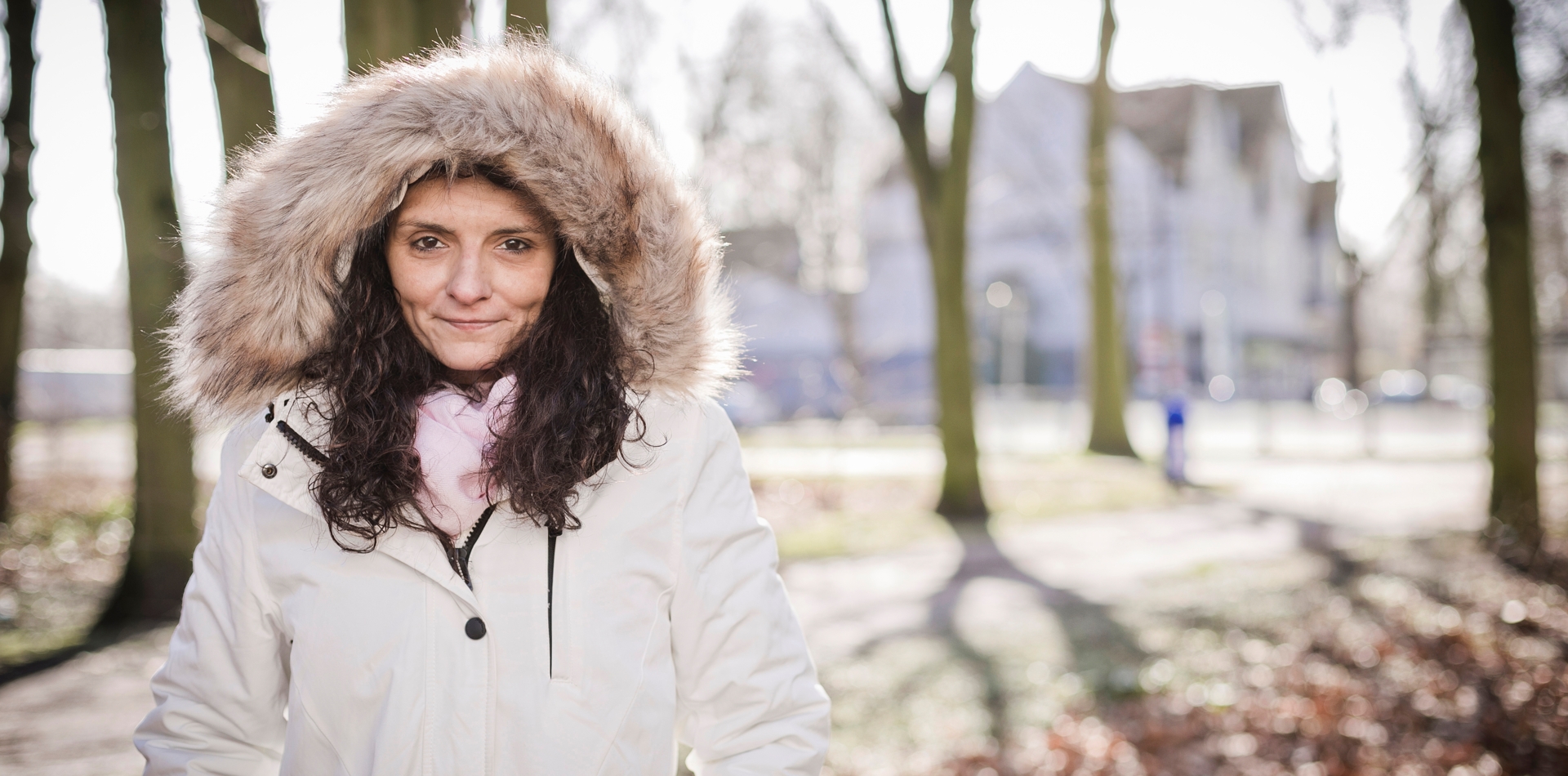 Eine Klientin von Bethel.regional steht zwischen kahlen Bäumen, Laub liegt am Boden.