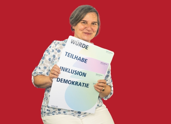 Frau mit Schildern Würde, Teilhabe, Inklusion und Demokratie.