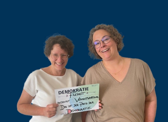 Zwei Frauen mit Schild in der Hand Demokratie Freiheit bedeutet Verantwortung. Das ist der Preis der Demokratie.