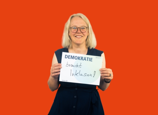 Frau mit Schild in der Hand Demokratie braucht Inklusion!