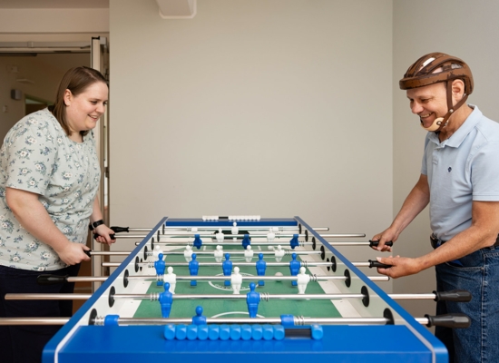 Bethel.regional_Mensch mit Epilepsie spielt mit einer Mitarbeiterin an einem Kickertisch_Haus Gihon Bethel.regional_Mensch mit Epilepsie spielt mit einer Mitarbeiterin an einem Kickertisch_Haus Gihon