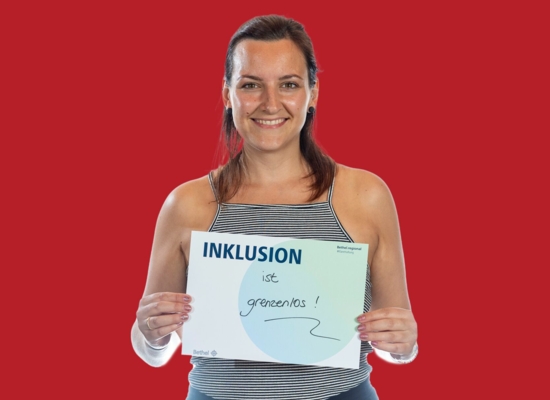 Frau mit Schild Inklusion ist grenzenlos!