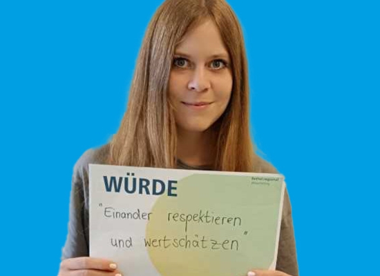 Frau mit Schild in der Hand Würde "Einander respektieren und wertschätzen".