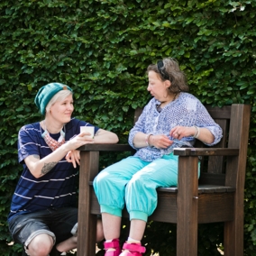 Junge Dame hockt neben einer Dame, die auf einem Stuhl sitzt